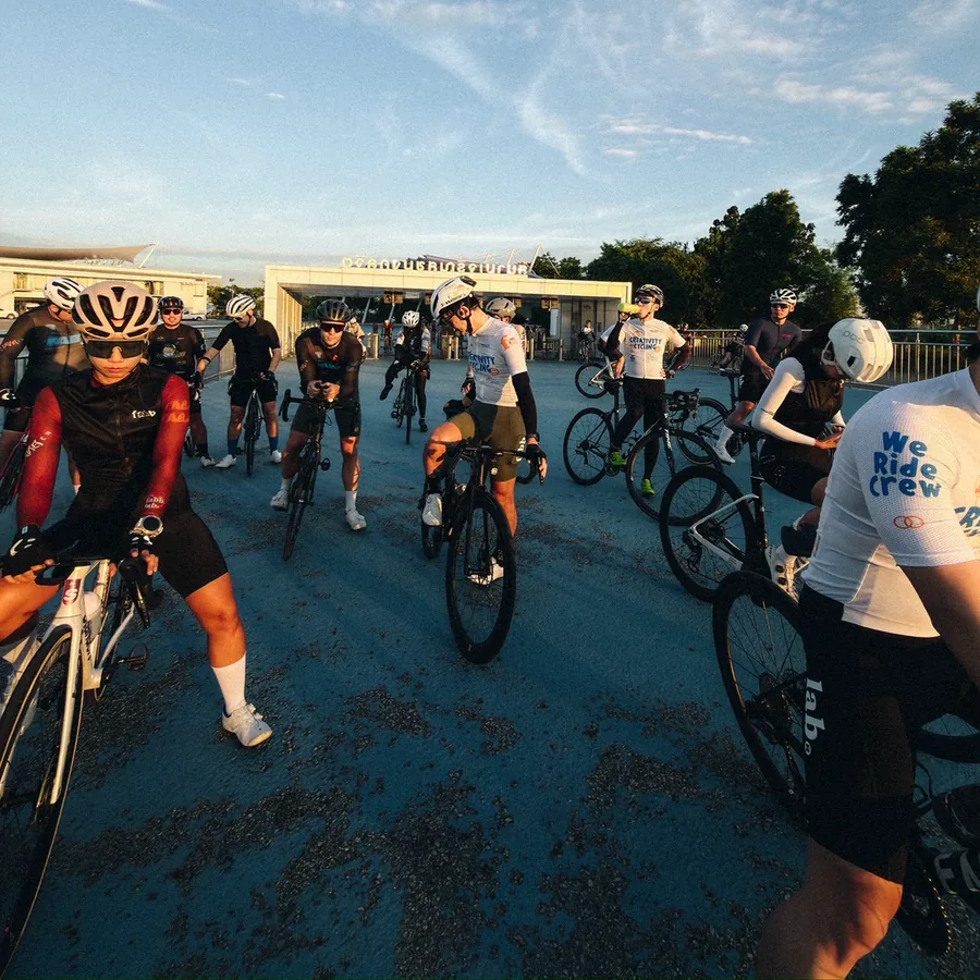 Riders regrouping with their bikes in an open plaza at golden hour